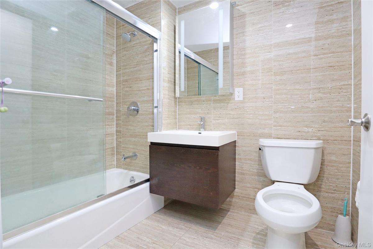 Bathroom featuring vanity, shower / bath combination with glass door, and tile walls