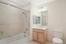 Updated 2nd bathroom with new glass shower doors, new bath light fixtures, vanity with wood cabinetry, and new white quartz countertop