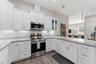 Open-concept kitchen with solid-wood cabinetry, granite countertops, stainless steel appliances, and custom lighting including under-counter kitchen l