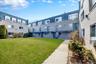 Courtyard-facing multi-unit residential building featuring a manicured lawn, concrete walkways, and established shrubbery