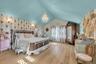 Bedroom featuring wallpapered walls, lofted ceiling, a chandelier, and wood finished floors