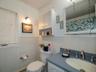 Full bath featuring vanity, crown molding, a baseboard heating unit, tile walls, and a wainscoted wall