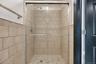Tiled shower stall featuring clear glass enclosure with brushed nickel hardware, a decorative wall tile band, and a matching tiled shower pan