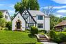 Tudor-style residence featuring a white stucco exterior with dark timber accents and a stone archway entrance