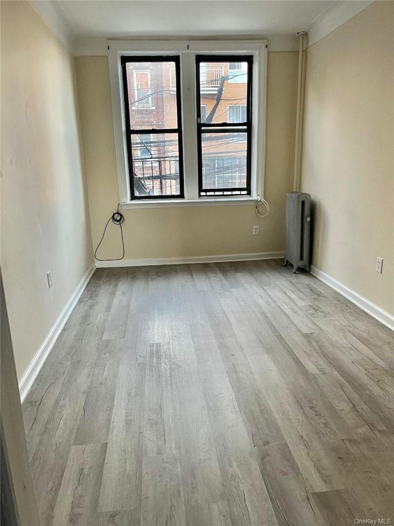 Spare room with radiator heating unit and light hardwood / wood-style flooring