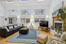 Living room with a towering ceiling, wood finished floors, and a high end fireplace