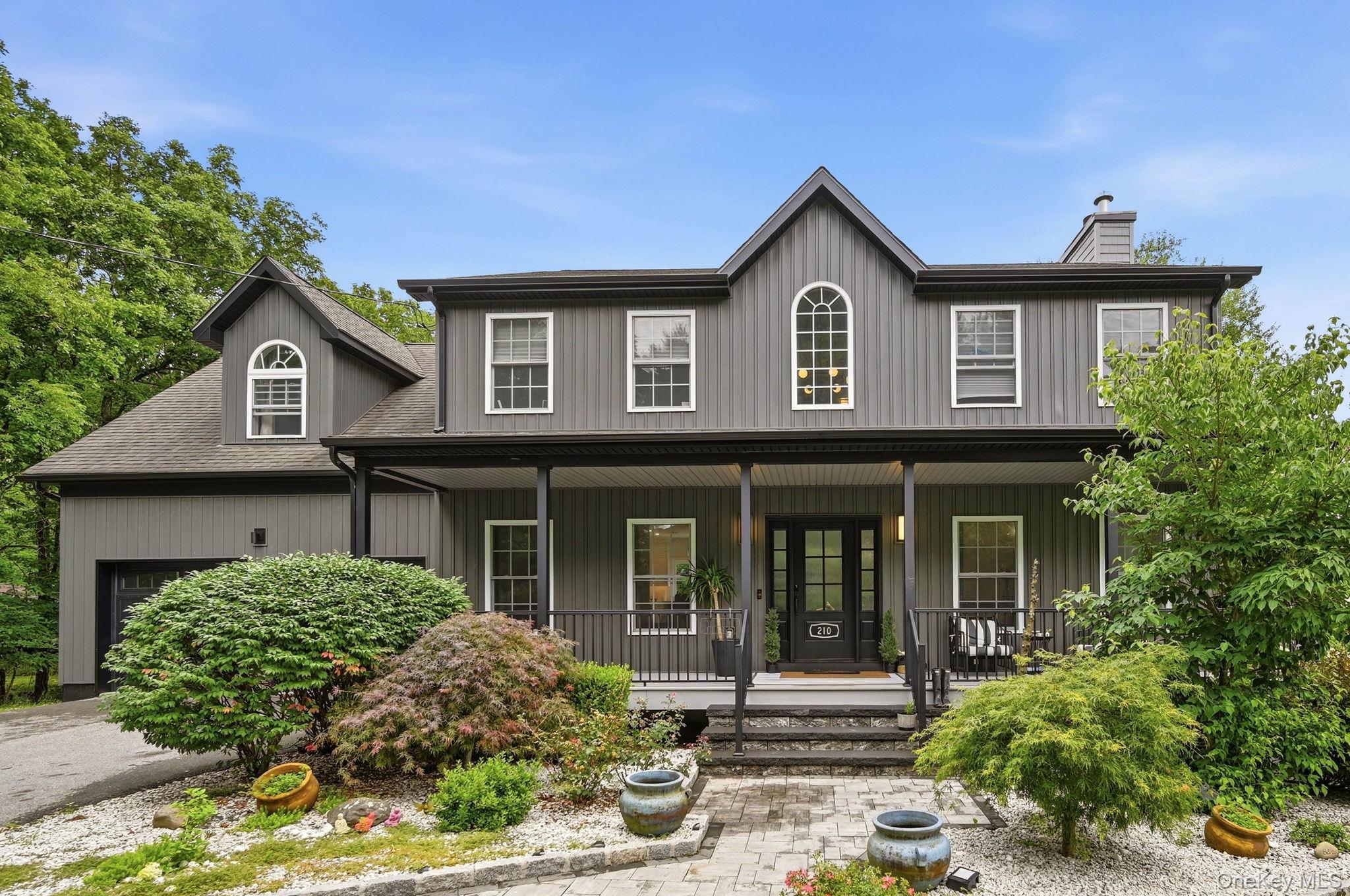 Two-story residence featuring vertical siding, a covered front porch, and an arched window