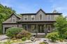 Two-story residence featuring vertical siding, a covered front porch, and an arched window
