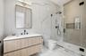 Full bath featuring stone wall, a marble finish shower, vanity, and light marble finish floors