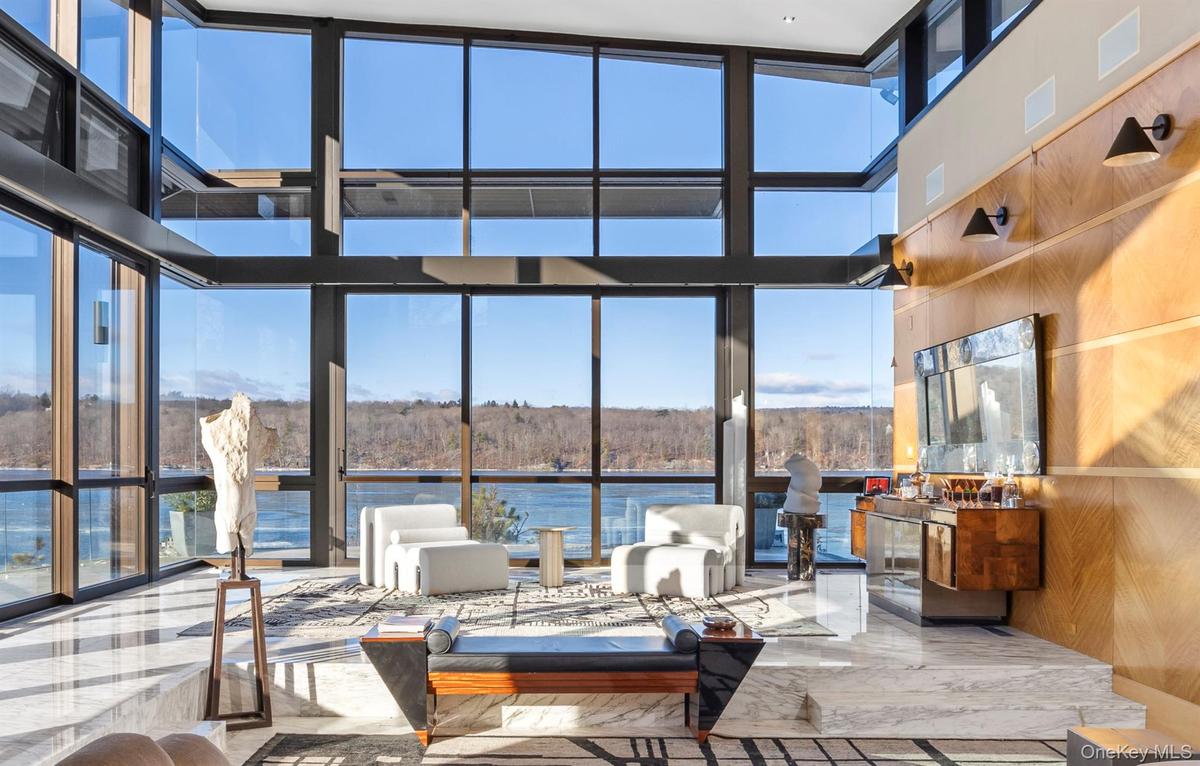 Living room with a fireplace, a towering ceiling, and a water view