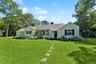 Ranch-style home with a chimney, a shingled roof, and cooling unit