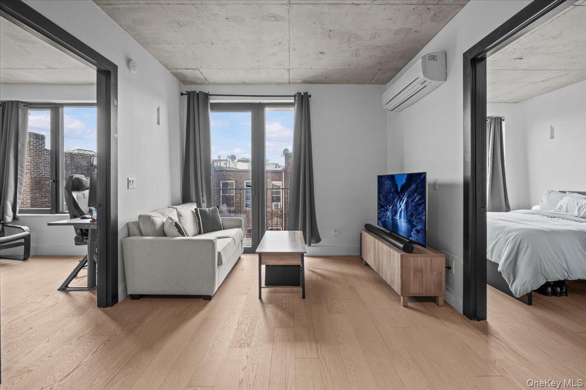Living room with light wood finished floors and a wall mounted AC
