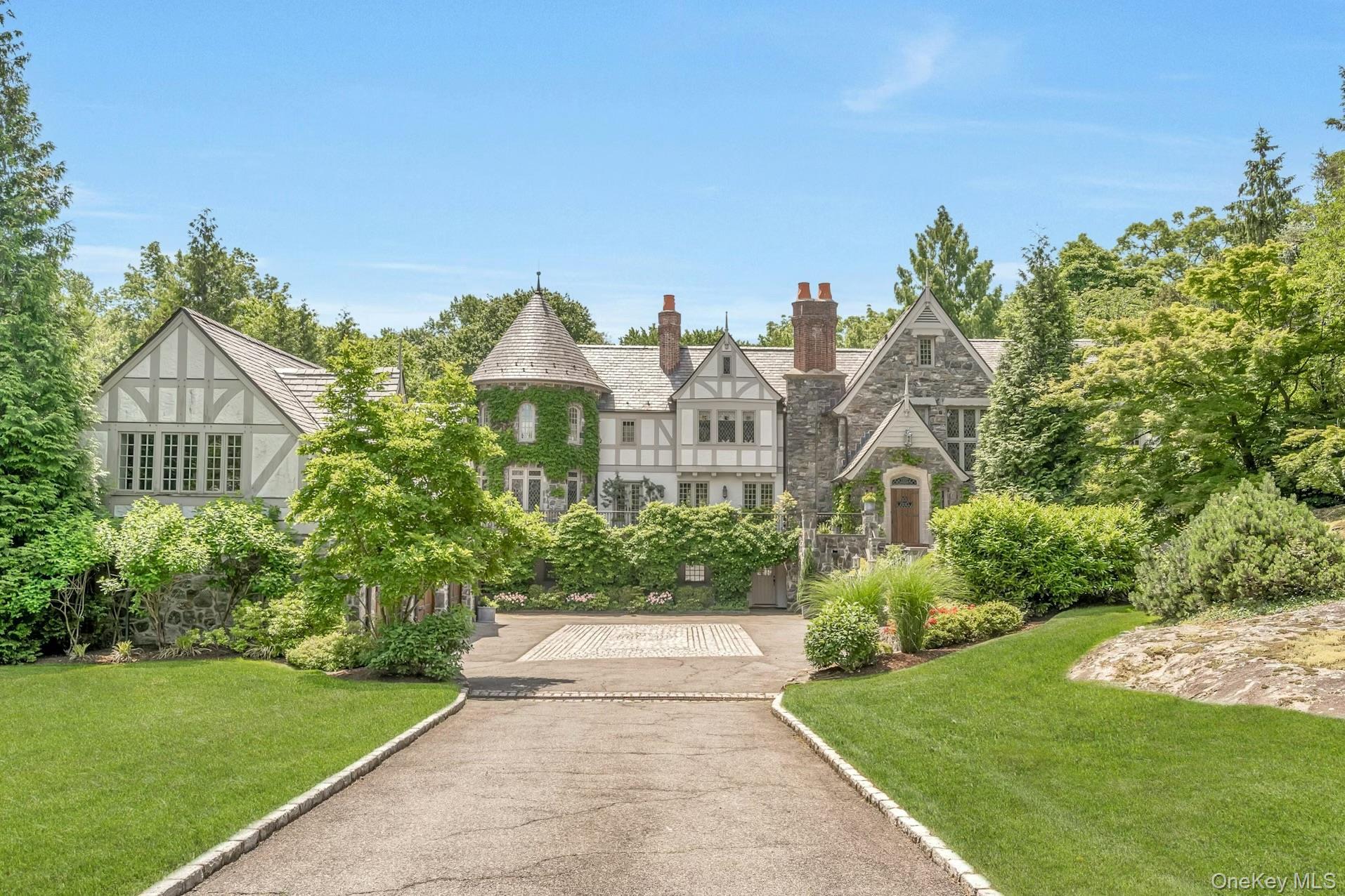 Elegant Tudor-style estate set on beautifully landscaped grounds featuring stone and half-timber architecture, a charming ivy-covered turret, and stat