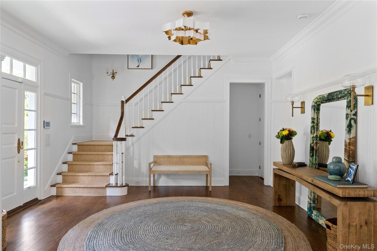 Foyer featuring wood finished floors, crown molding, and stairs