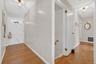 Hall featuring light wood-type flooring, an upstairs landing, and wood walls