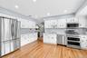 Kitchen with appliances with stainless steel finishes, white cabinetry, recessed lighting, light wood-type flooring, and open shelves
