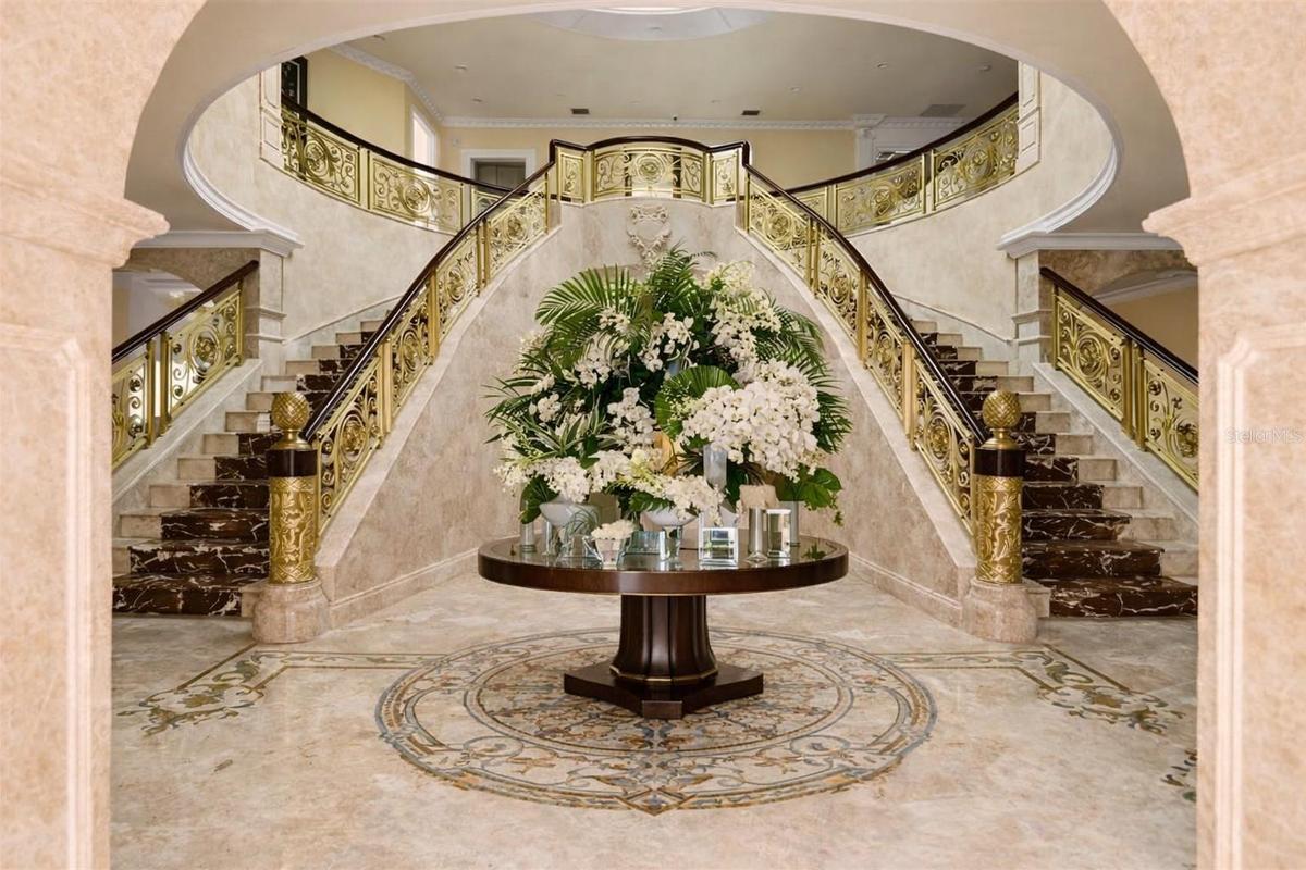 Dramatic rotunda with statement chandelier and marble staircases.