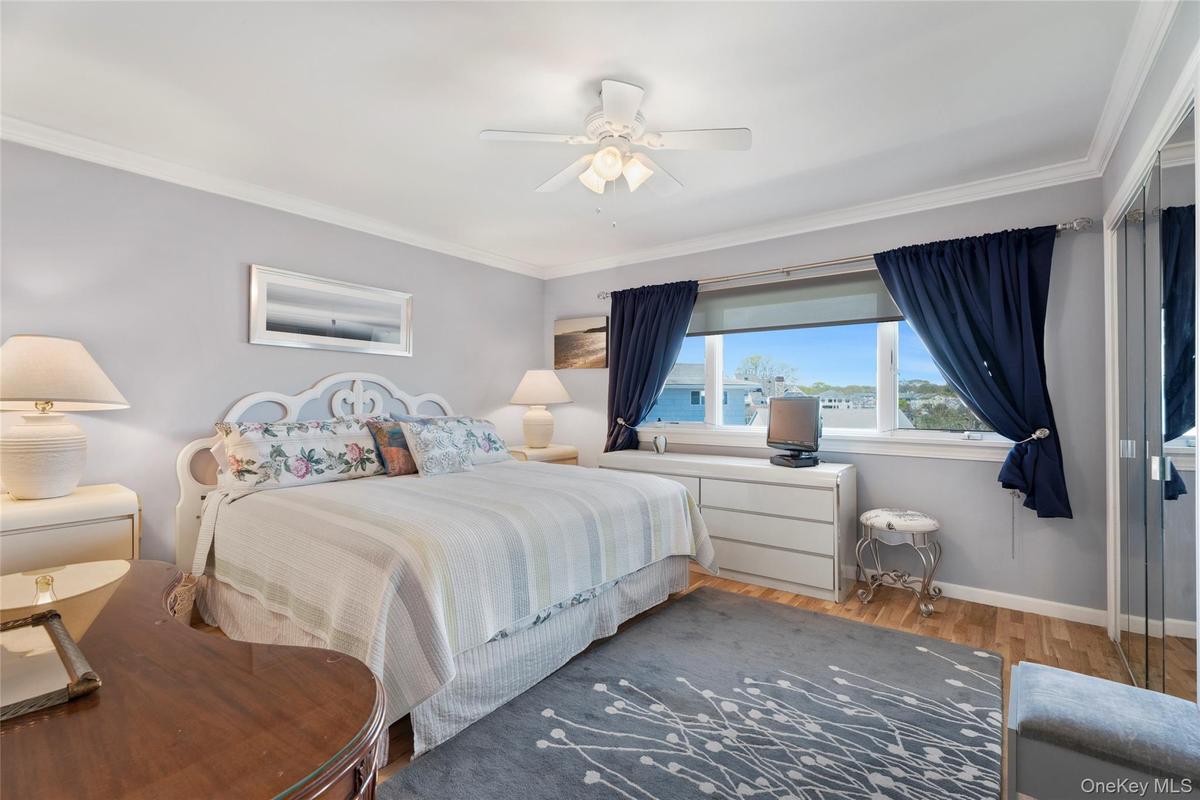 Bedroom featuring wood finished floors, crown molding, baseboards, and a ceiling fan