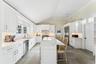 Kitchen featuring a kitchen breakfast bar, lofted ceiling, white cabinets, light quartz counters, and a kitchen island.