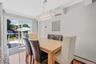 Dining room featuring a baseboard radiator, ornamental molding, wood finished floors, a wall unit AC, and a chandelier