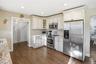 Kitchen with appliances with stainless steel finishes, dark wood finished floors, light stone counters, glass insert cabinets, and recessed lighting