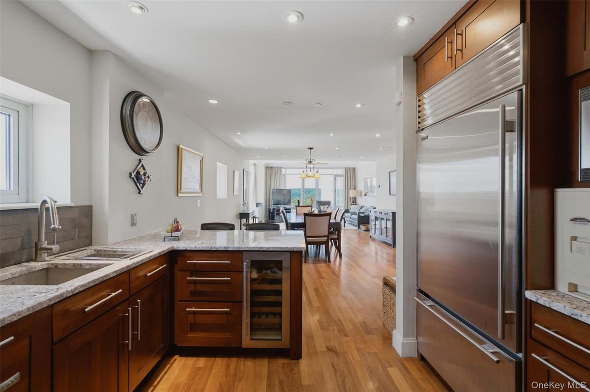 Kitchen featuring wood cabinetry, stainless steel appliances, granite countertops, and hardwood flooring