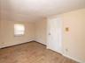 Spare room featuring a baseboard radiator, light wood-style floors, lofted ceiling, and baseboard heating