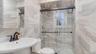 Bathroom with a shower stall, toilet, a sink, and tile walls