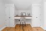 Office area with built in study area, light wood finished floors, and baseboards