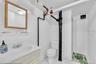 White-tiled bathroom featuring a white vanity with integrated sink, a wood-framed mirror, and a toilet
