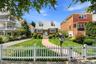 Brick exterior home featuring a gabled roof, white picket fence, and a curved brick pathway