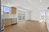 Kitchen featuring modern cabinets, appliances with stainless steel finishes, decorative backsplash, light stone countertops, and light wood finished f