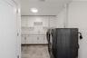 This spacious, well-appointed laundry room combines function and style with sleek cabinetry, quartz countertops, and abundant storage. A deep sink and