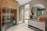 Private wellness suite featuring cedar wood sauna with glass door and LED bench lighting, adjacent frameless glass steam shower with marble tile surro