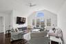 Living area featuring visible vents, baseboards, a ceiling fan, dark wood finished floors, and vaulted ceiling