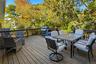 Wooden terrace featuring outdoor dining area, a grill, and view of scattered trees