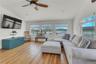 Living room with lofted ceiling, plenty of natural light, wood finished floors, ceiling fan, and a water view