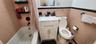 Full bath featuring tile walls, toilet, shower / bathtub combination with curtain, a wainscoted wall, and vanity