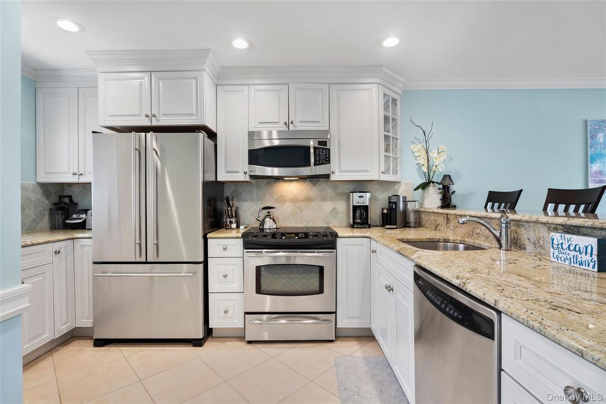 Kitchen featuring white cabinets, a sink, appliances with stainless steel finishes, and tasteful backsplash