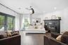 A bright and inviting family room featuring rich hardwood floors, recessed lighting and a contemporary ceiling fan. A striking fireplace with a bold d