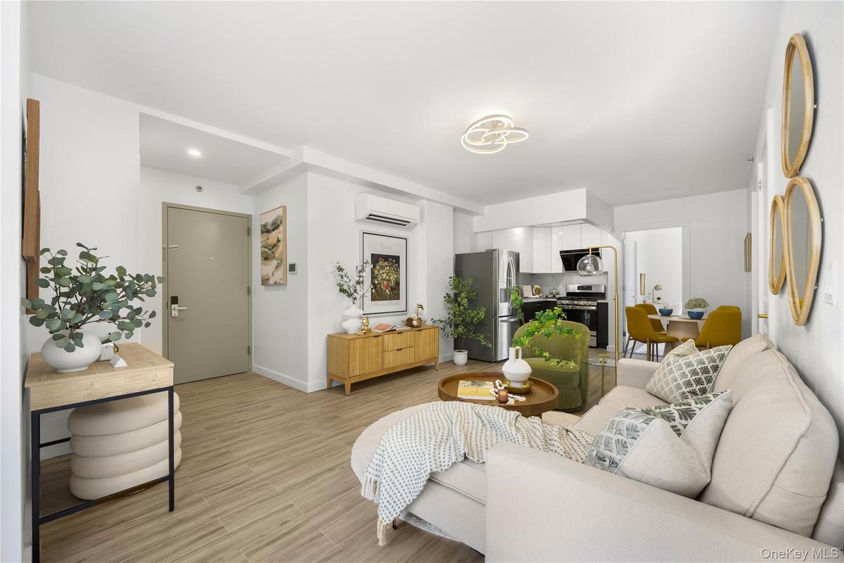 Living area with baseboards, light wood-style flooring, and a wall mounted AC