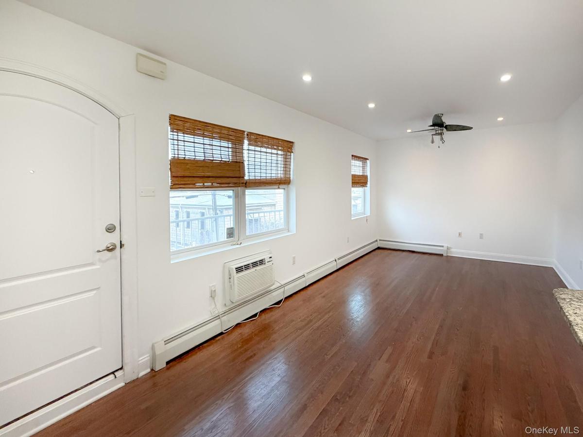 Spare room with recessed lighting, dark wood finished floors, ceiling fan, an AC wall unit, and a baseboard radiator