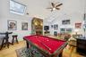 Recreation room with a skylight, lofted ceiling, billiards, a stone fireplace, and light wood finished floors