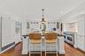 Gourmet chef’s kitchen with custom white cabinetry, premium stainless steel appliances, and an oversized island with seating. Elegant finishes, warm h