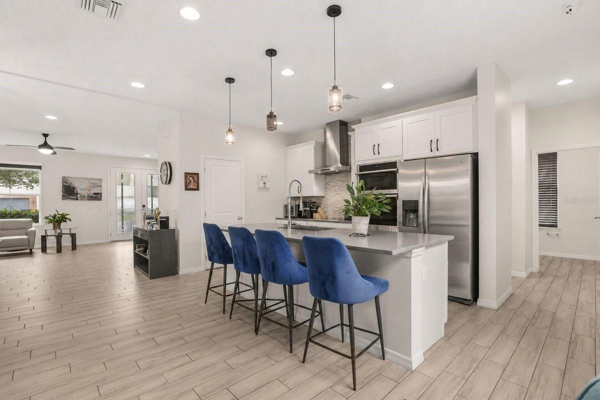 Alternate view of the spacious kitchen showcasing the oversized center island with seating and its seamless connection to the open living areas.