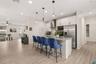 Alternate view of the spacious kitchen showcasing the oversized center island with seating and its seamless connection to the open living areas.
