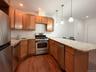 Kitchen featuring appliances with stainless steel finishes, light stone counters, recessed lighting, pendant lighting, and dark wood finished floors