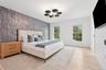 Bedroom with an accent wall, wallpapered walls, a chandelier, light wood-style floors, and baseboards