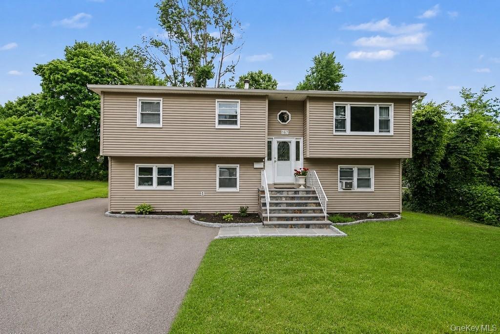 Split-level residence featuring tan vinyl siding and white trim windows