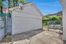 Detached garage with a paneled door, concrete driveway, and a partially fenced yard with concrete steps